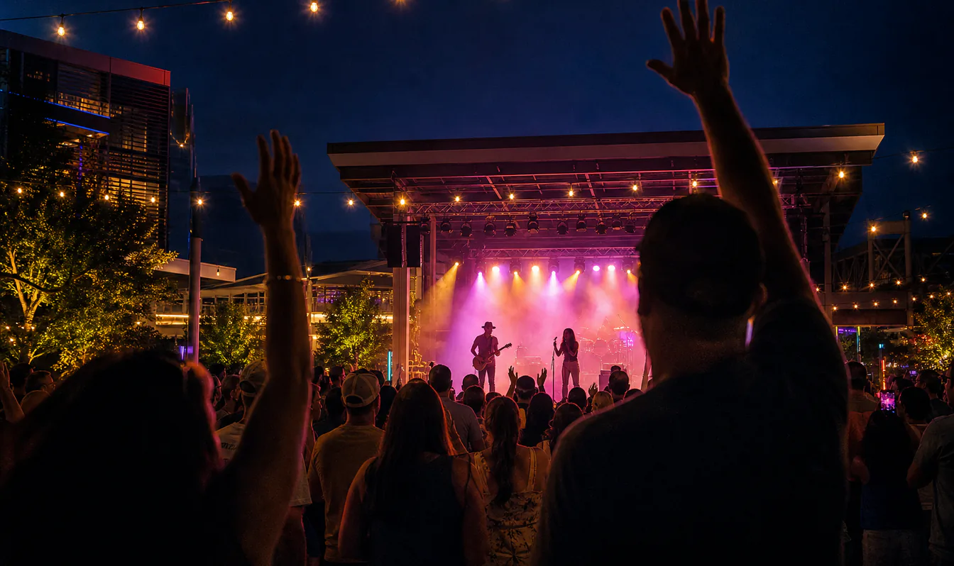 An editorial image of a crowd enjoying a tribute-band concert in an outdoor plaza on a summer night